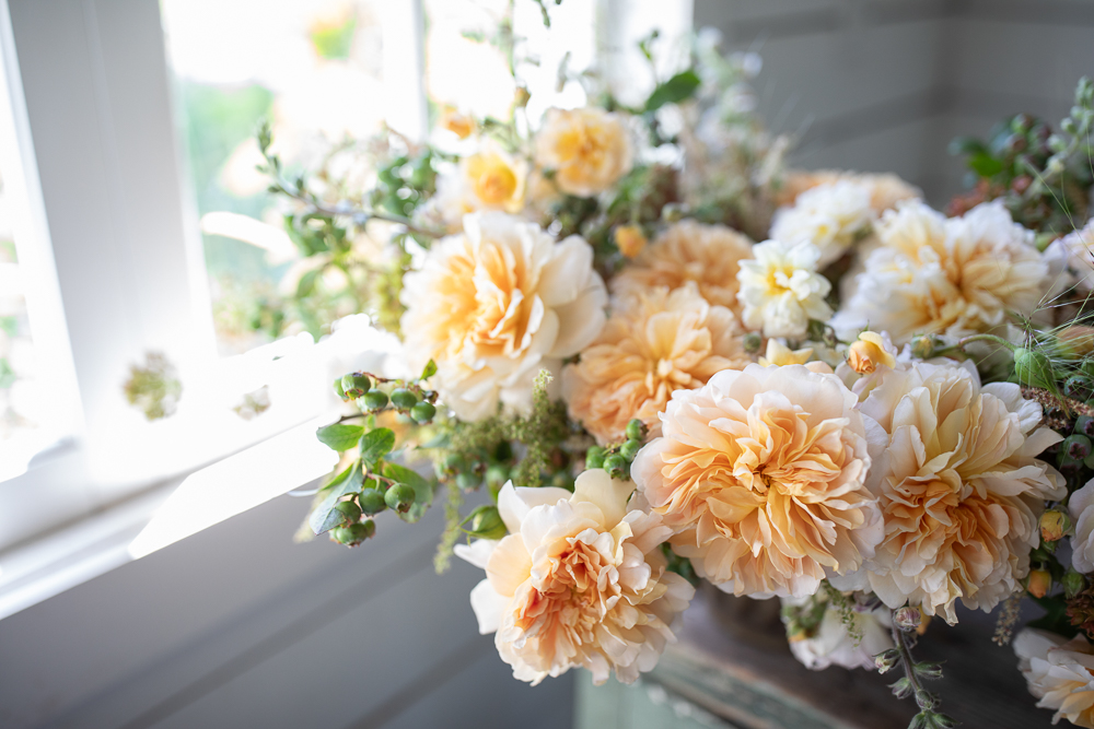 Close up of a seasonal arrangement featuring peach garden roses